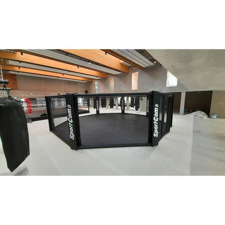 SportCom MMA-Trainingskäfig zur Bodenmontage, in einem Dachgeschoss-Gym mit Boxsäcken