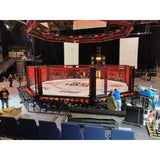 SportCom MMA-Wettkampfkäfig 7 m mit 9-m-Laufsteg, mit rot beleuchtetem Podium in einer Arena