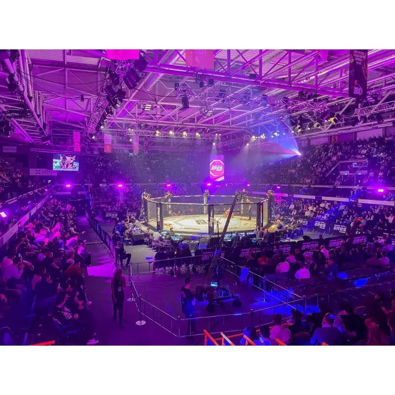 SportCom MMA-Wettkampfkäfig 7 m mit 9-m-Laufsteg, in einer violett beleuchteten Halle, Blick von oben