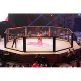 SportCom MMA-Wettkampfkäfig 7 m mit 9-m-Laufsteg, während eines Kampfes mit roter Bühnenbeleuchtung