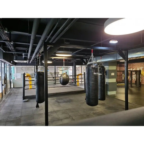 SportCom Modulare Sandsack-Station, in einem Gym mit Boxring und runder Deckenleuchte