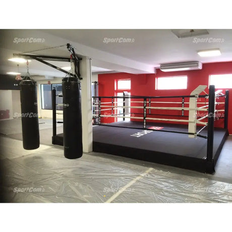 SportCom Pro-Trainingsboxring mit 30 cm Podium, mit Boxsäcken vor roter Wand