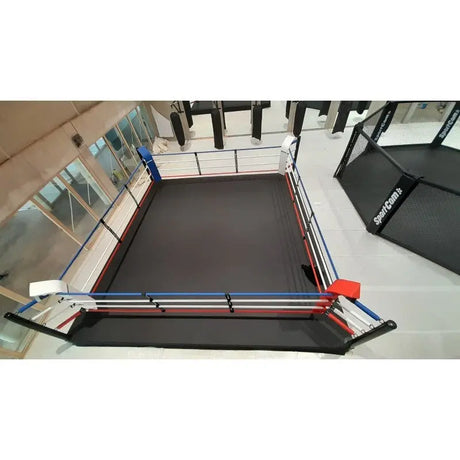 SportCom Pro-Trainingsboxring mit 30 cm Podium, von oben in einem Studio mit Käfig im Hintergrund