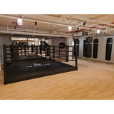SportCom Pro-Trainingsboxring mit 30 cm Podium, in einem Gym mit Boxsäcken und Holzboden