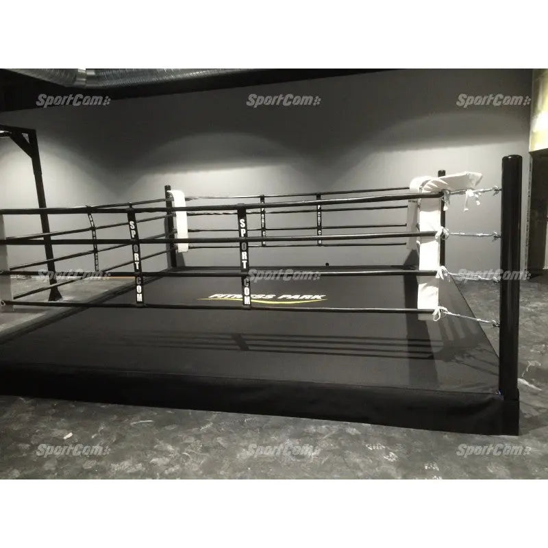 SportCom Pro-Trainingsboxring mit 30 cm Podium, in einer dunklen Halle mit schwarzen Seilen