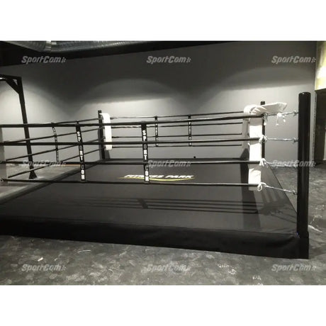 SportCom Pro-Trainingsboxring mit 30 cm Podium, in einer dunklen Halle mit schwarzen Seilen