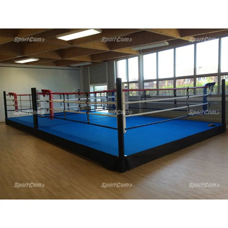 SportCom Pro-Trainingsboxring mit 30 cm Podium, mit blauem Boden in einer hellen Halle mit Fensterfront