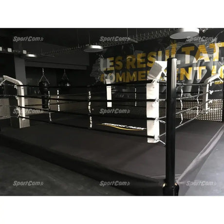 SportCom Pro-Trainingsboxring mit 30 cm Podium, in einer Halle mit Wandschrift, schwarzer Boden