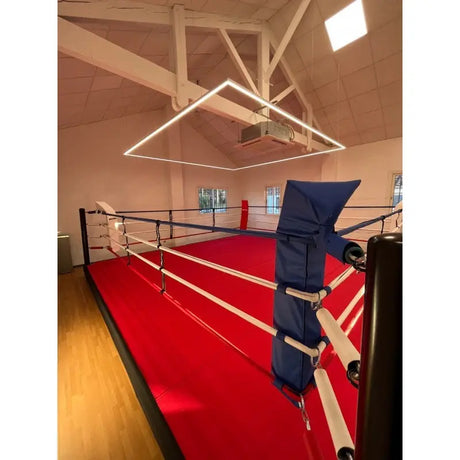 SportCom Pro-Trainingsboxring mit 30 cm Podium, mit rotem Boden, Blick entlang der Seile zum Eckpolster