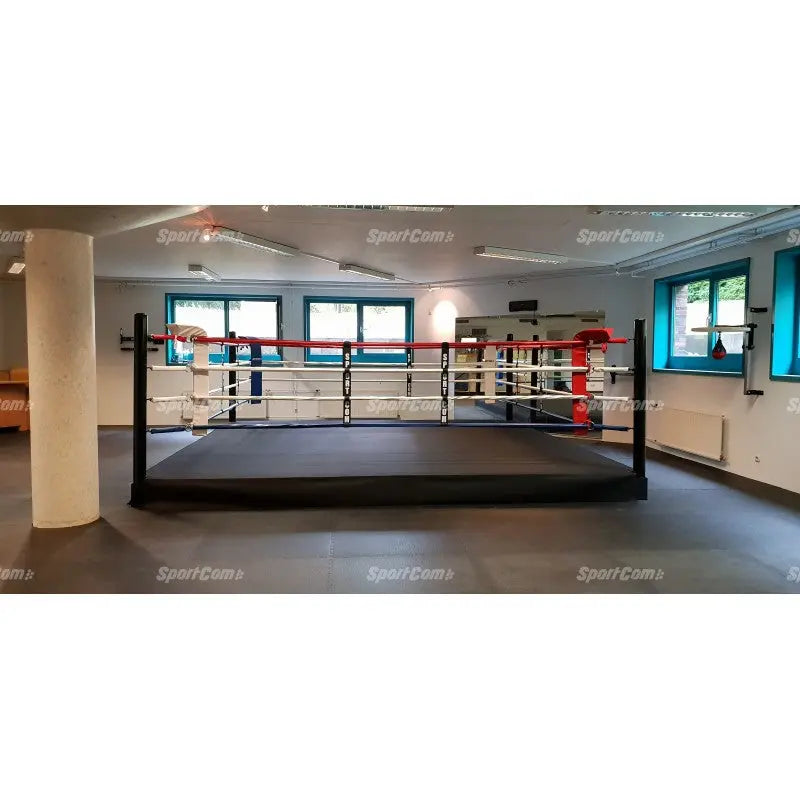 SportCom Pro-Trainingsboxring mit 30 cm Podium, in einem hellen Trainingsraum mit rot-blauen Ecken