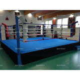 SportCom Pro-Trainingsboxring mit 50 cm Podium, mit blauem Boden in einem Gym mit grünem Boden
