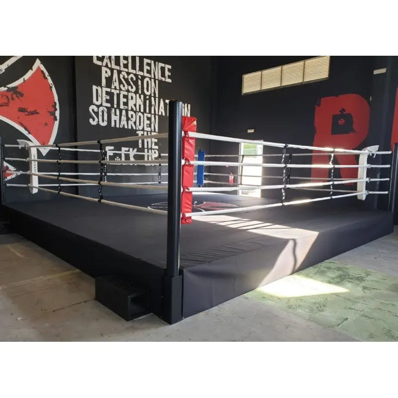 SportCom Pro-Trainingsboxring mit 50 cm Podium, in einem Gym mit Wandschriftzug, schwarzes Podium
