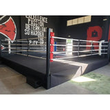 SportCom Pro-Trainingsboxring mit 50 cm Podium, in einem Gym mit Wandschriftzug, schwarzes Podium