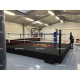 SportCom Pro-Trainingsboxring mit 50 cm Podium, in einer Halle mit blauer Ecke und Logo