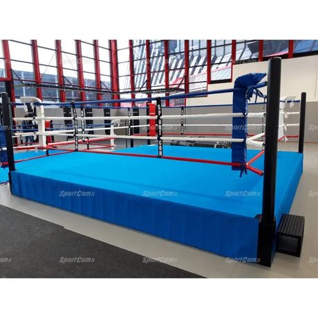 SportCom Pro-Trainingsboxring mit 50 cm Podium, mit blauem Boden in einer Halle mit roten Streben
