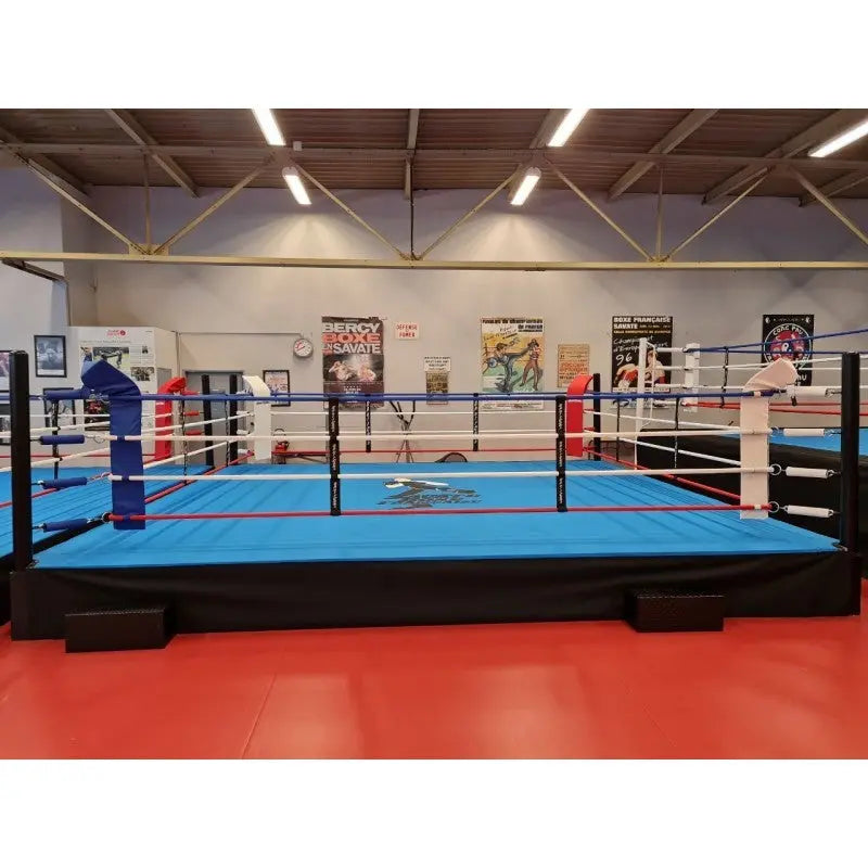 SportCom Pro-Trainingsboxring mit 50 cm Podium, mit blauem Boden in einer Halle mit rotem Boden