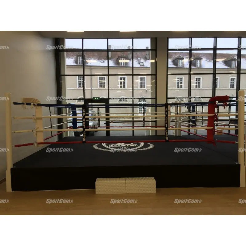 SportCom Pro-Trainingsboxring mit 50 cm Podium, in einer Halle vor großen Fenstern mit Treppe