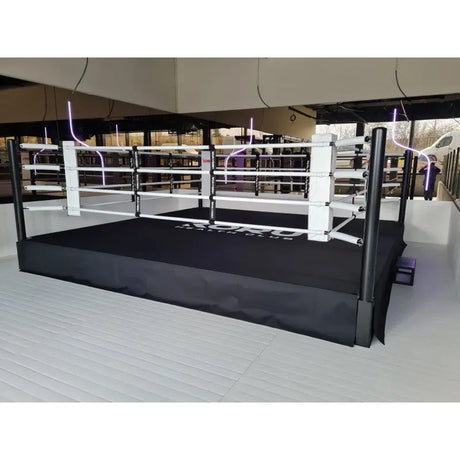 SportCom Pro-Trainingsboxring mit 50 cm Podium, in einer Halle mit weißen Eckpolstern, seitlich