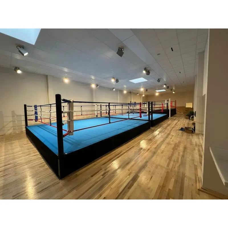 SportCom Pro-Trainingsboxring mit 50 cm Podium, mit blauem Boden in einem Raum mit Parkett