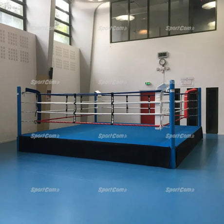 SportCom Pro-Trainingsboxring mit 50 cm Podium, mit blauem Boden in einer hellen Sporthalle