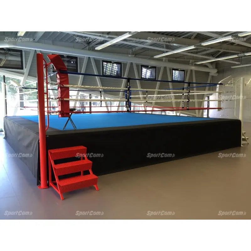 SportCom Pro-Wettkampf-Boxring mit 1 m Podium, mit roter Treppe und blauer Fläche in der Halle