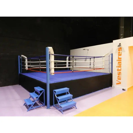 SportCom Pro-Wettkampf-Boxring mit 1 m Podium, mit zwei blauen Treppen vor dunkler Wand
