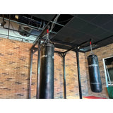 SportCom Proboxe Wandstation für Sandsäcke, vor Backsteinwand mit zwei Sandsäcken