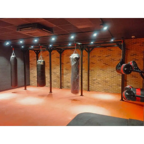 SportCom Proboxe Wandstation für Sandsäcke, in einem Gym mit orangefarbenem Boden und Spots