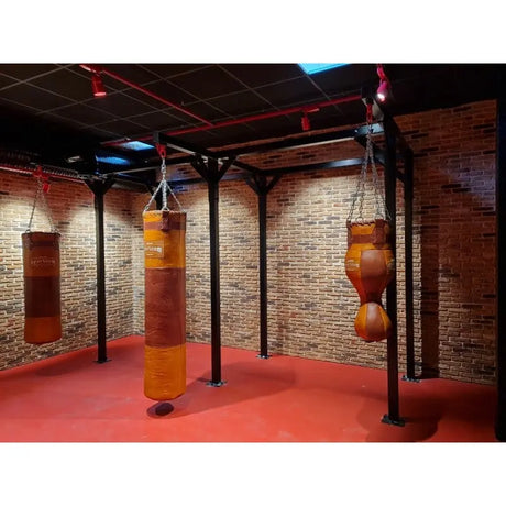 SportCom Proboxe Wandstation für Sandsäcke, mit Ledersäcken vor Backsteinwand