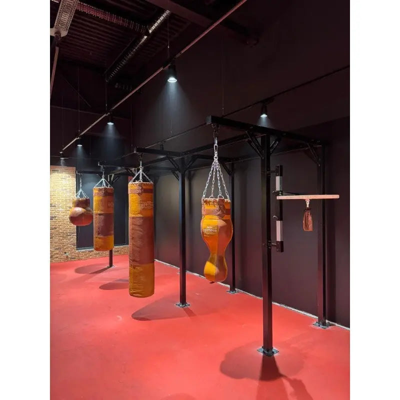 SportCom Proboxe Wandstation für Sandsäcke, mit Ledersäcken in einem Raum mit schwarzen Wänden