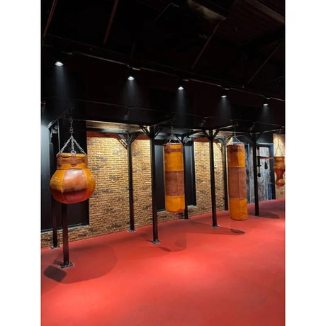 SportCom Proboxe Wandstation für Sandsäcke, mit Ledersäcken vor Backsteinwand, seitlich