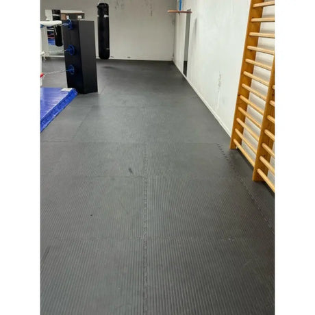 SportCom Puzzlematten 2 cm in Schwarz als verlegter Boden im Trainingsraum mit Sprossenwand