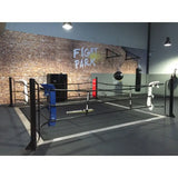 SportCom Ringplane für Bodenmontage-Boxringe – Schwarze Plane im Ring mit blauen und roten Ecken in der Halle
