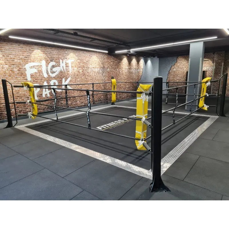 SportCom Ringplane für Bodenmontage-Boxringe – Schwarze Plane im Ring mit gelben Eckpolstern in einer Trainingshalle