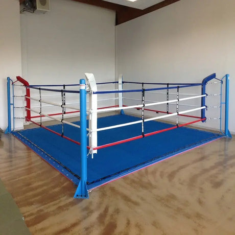 SportCom Ringplane für Bodenmontage-Boxringe – Blaue Plane im Ring auf Parkettboden mit rot-weißen Seilen