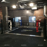 SportCom Ringplane für Bodenmontage-Boxringe – Schwarze Plane im Boxring eines Studios mit Backsteinwand