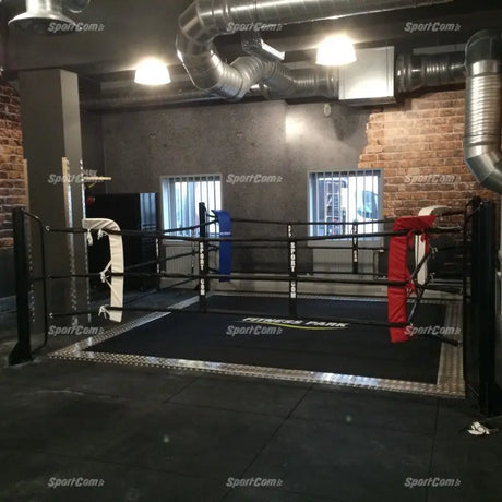 SportCom Ringplane für Bodenmontage-Boxringe – Schwarze Plane im Boxring eines Studios mit Backsteinwand