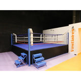 SportCom Ringplane für Wettkampf-Boxringe: Ring mit dunkelblauer Plane und zwei Treppen vor Umkleiden