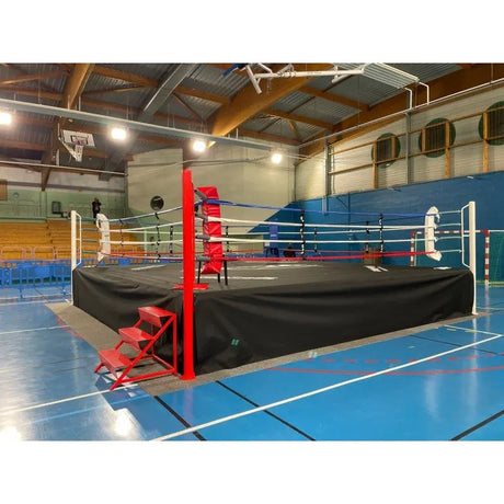SportCom Ringplane für Wettkampf-Boxringe: Ring mit schwarzer Plane in einer Sporthalle mit rotem Pfosten