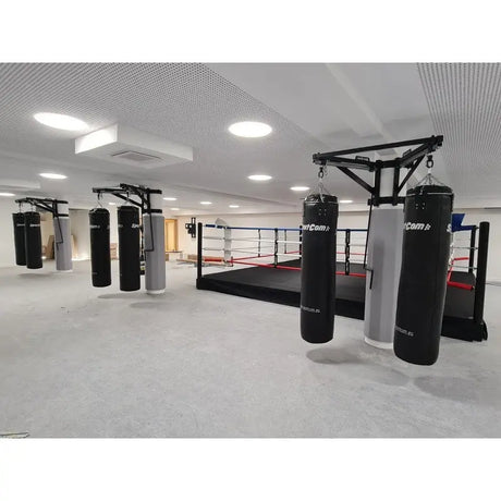 SportCom Sandsack-Wandhalterung mit Schiene und Laufwagen als freistehende Konstruktion vor dem Boxring in heller Halle