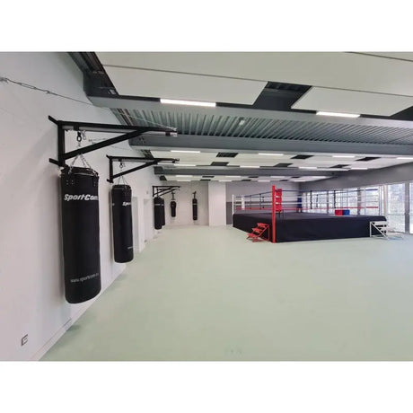 SportCom Sandsack-Wandhalterung mit Schiene und Laufwagen in einer hellen Halle mit Boxring im Hintergrund, Wandreihe