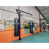 SportCom Sandsack-Wandhalterung mit Schiene und Laufwagen mit Sandsäcken entlang einer orangen Wand, Blick in die Halle
