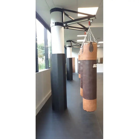 SportCom Sandsack-Wandhalterung mit Schiene und Laufwagen an einer Säule mit braunem Sandsack neben Fenstern