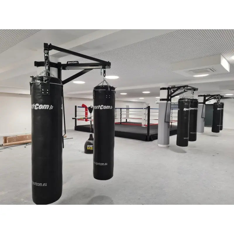 SportCom Sandsack-Wandhalterung mit Schiene und Laufwagen mit zwei Sandsäcken vor Boxring und weiteren Stationen