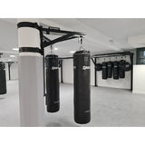 SportCom Sandsack-Wandhalterung mit Schiene und Laufwagen an einer weißen Säule mit zwei Sandsäcken in der Trainingshalle