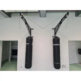 SportCom Sandsack-Wandhalterung mit Schiene und Laufwagen mit zwei Wandauslegern und Sandsäcken an einer weißen Wand