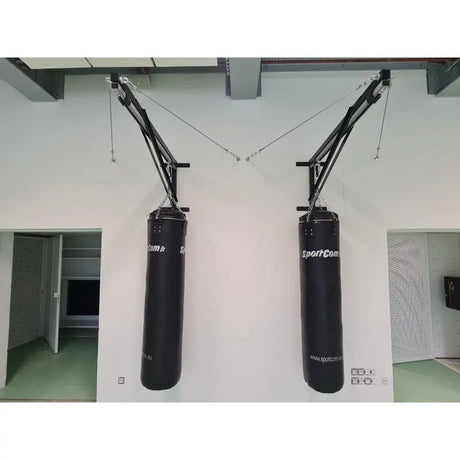 SportCom Sandsack-Wandhalterung mit Schiene und Laufwagen mit zwei Wandauslegern und Sandsäcken an einer weißen Wand