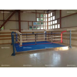 SportCom Trainingsboxring mit 15 cm Podium, in einer Halle mit Holzwand und blauem Boden