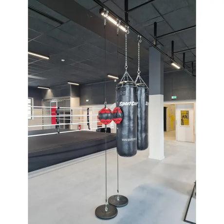 SportCom Überkopf-Förderschiene für Sandsäcke, in einem Gym mit Boxring und Punchingbällen