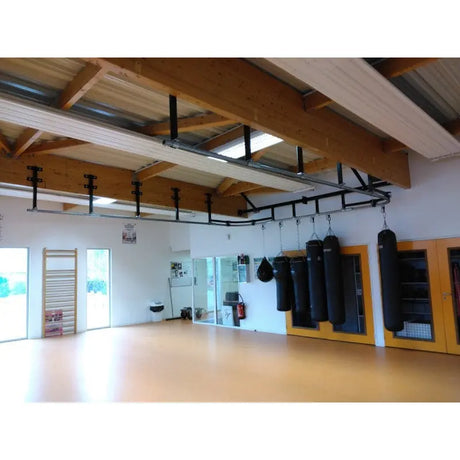 SportCom Überkopf-Förderschiene für Sandsäcke, in einer Halle mit Holzträgern und Sprossenwand